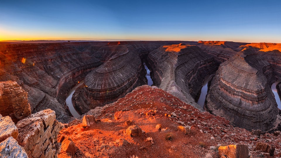 A canyon with layered rock formations and a river running through it.