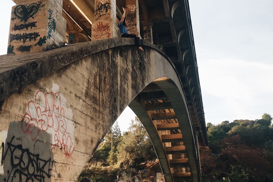 A bridge with graffiti and a river below.