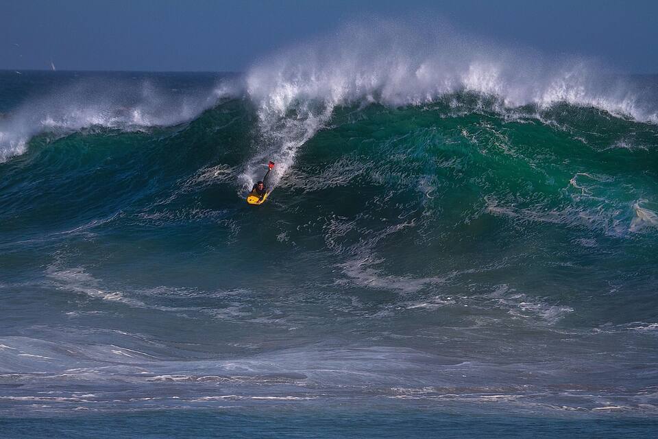 En surfer rider en stor bølge i havet.