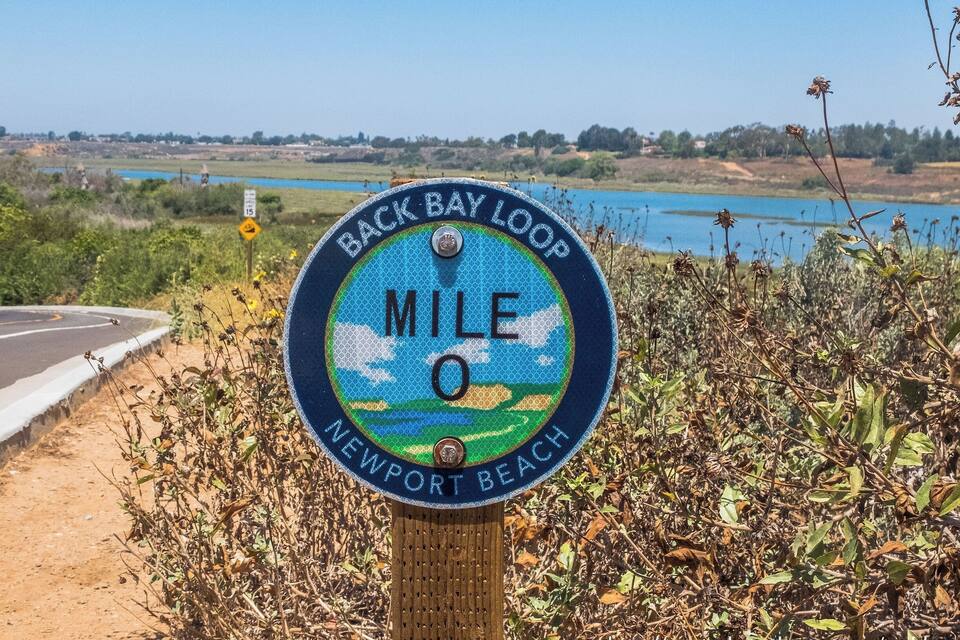 Naamplaatje dat de Back Bay Loop, Newport Beach aangeeft, met een mooi uitzicht op de oceaan en een weg.