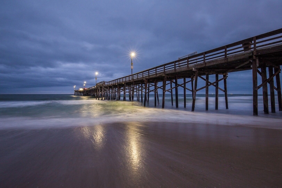 A wooden pier extending into the ocean at dusk.