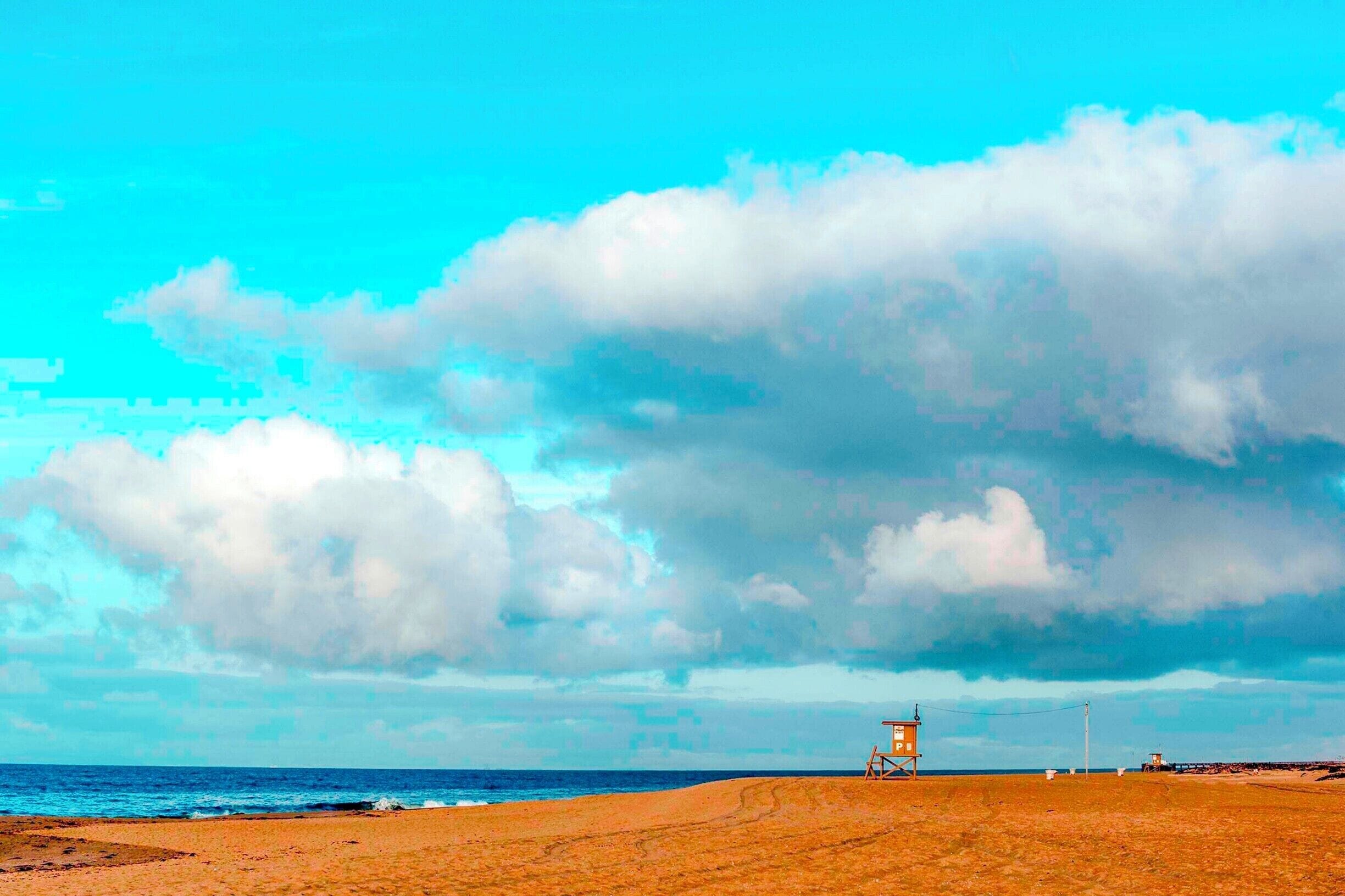 "P" Street, guard tower stands in solitude along an empty shore at the end of the Balboa Peninsula under stormy skies.