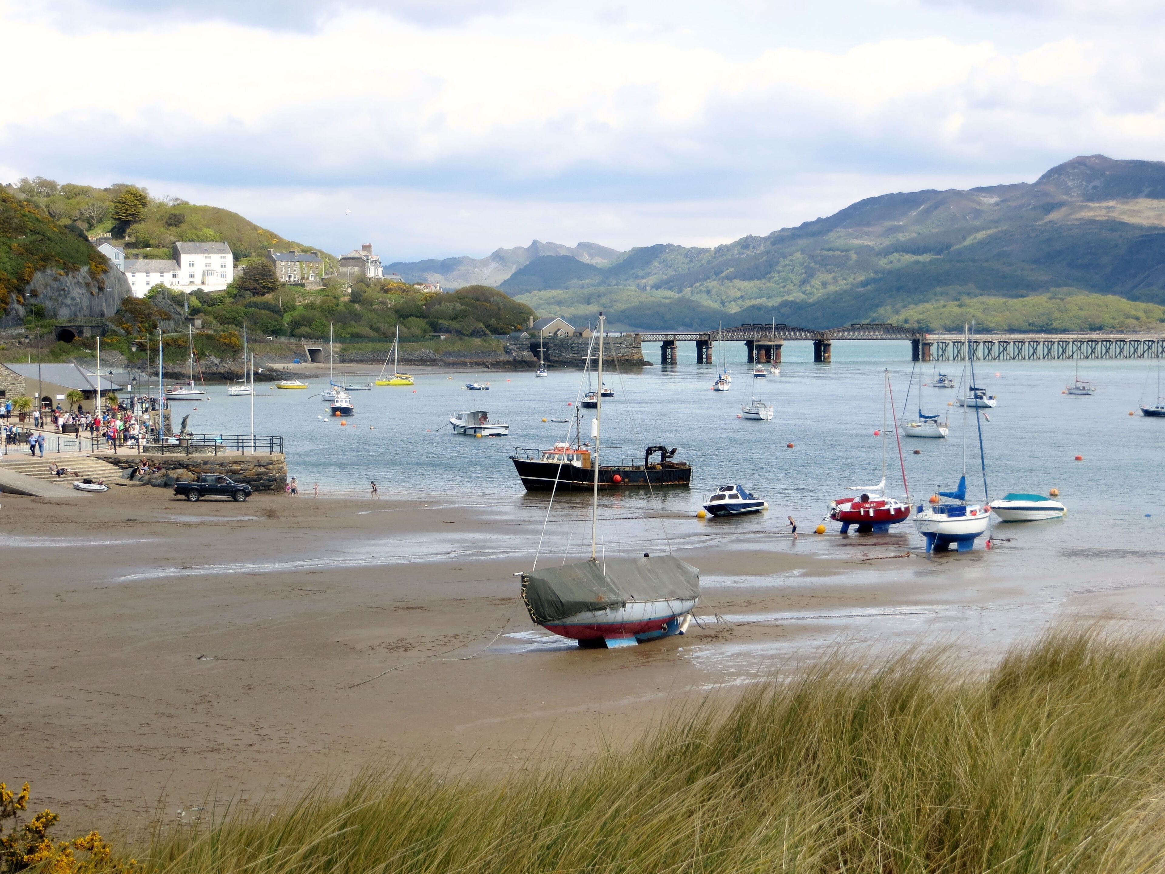 A coastal scene with boats, a pier, and a mountainous backdrop.
