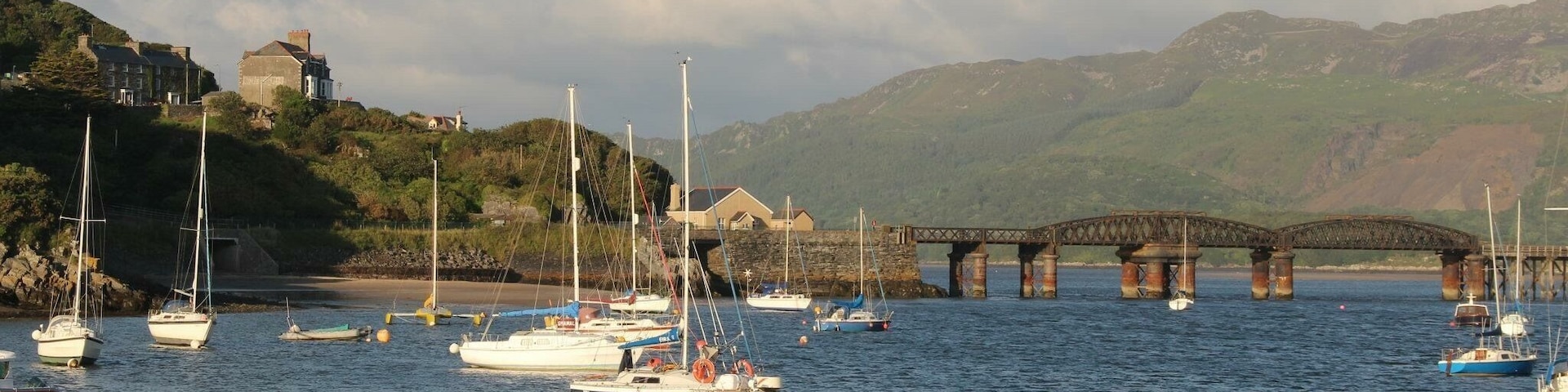 Un puerto con barcos, un puente y una colina con edificios.