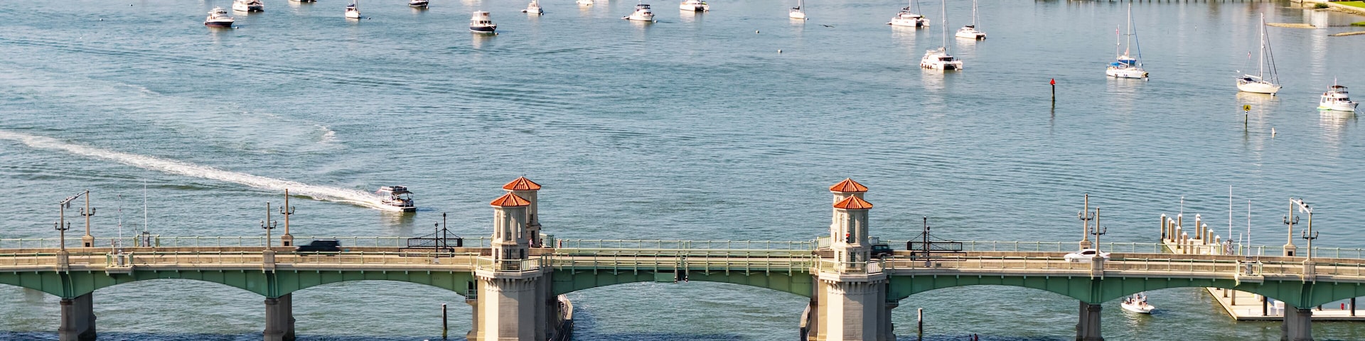 An aerial view of the Bridge of Lions in St. Augustine, FL. This decorative bridge spans the Matanzas River and connects the historic city to Anastasia Island. Sailboats fill the river.