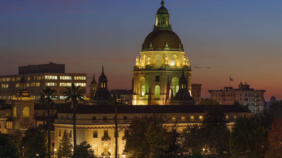 A grand building with a prominent dome and multiple towers, surrounded by trees and other structures.