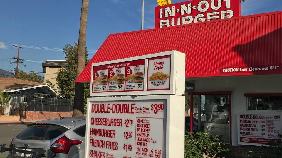 Un restaurante de comida rápida con toldo rojo y un letrero que dice "IN-N-OUT BURGER".