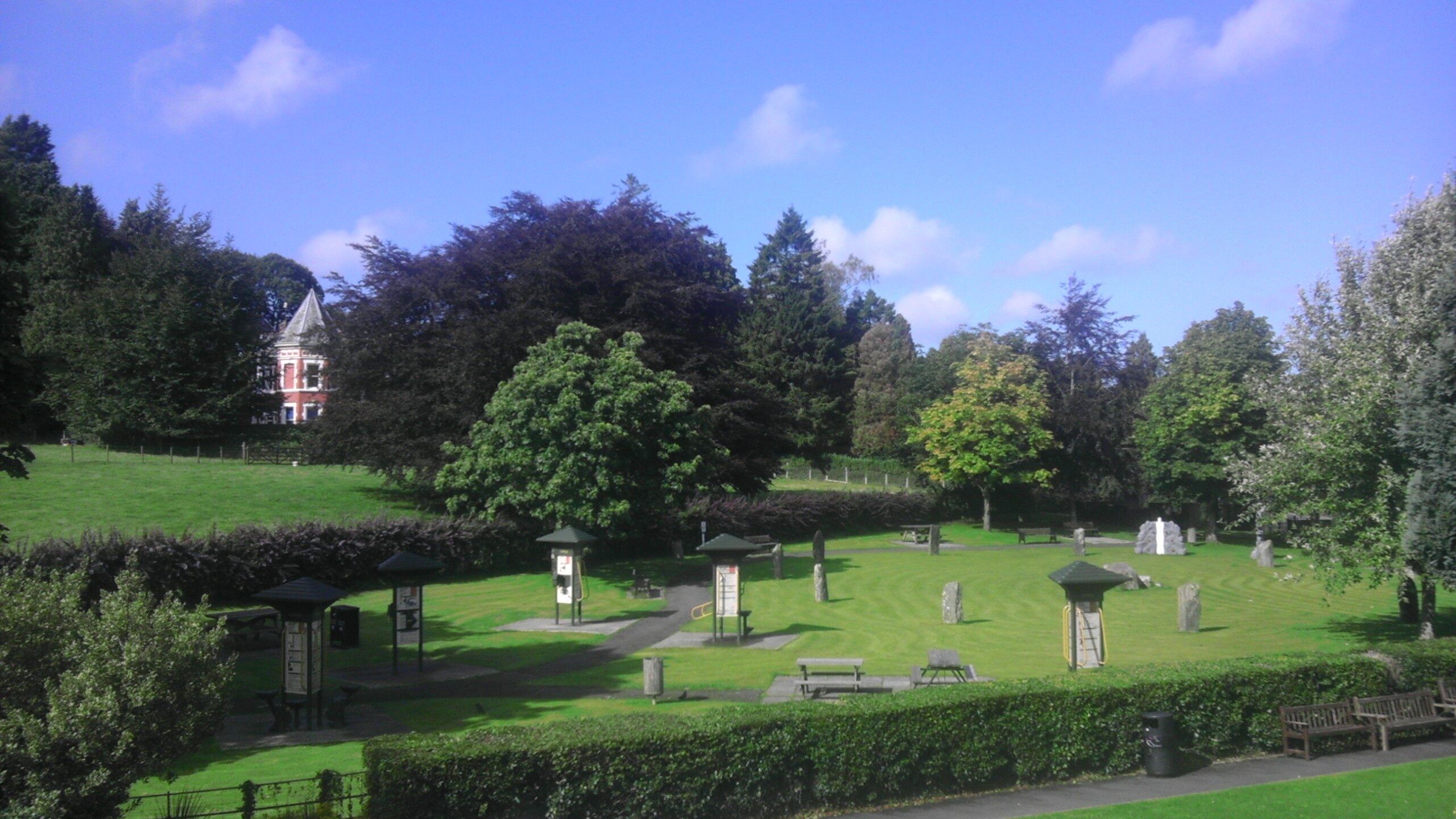 A cemetery with headstones, a gazebo, and a large tree.