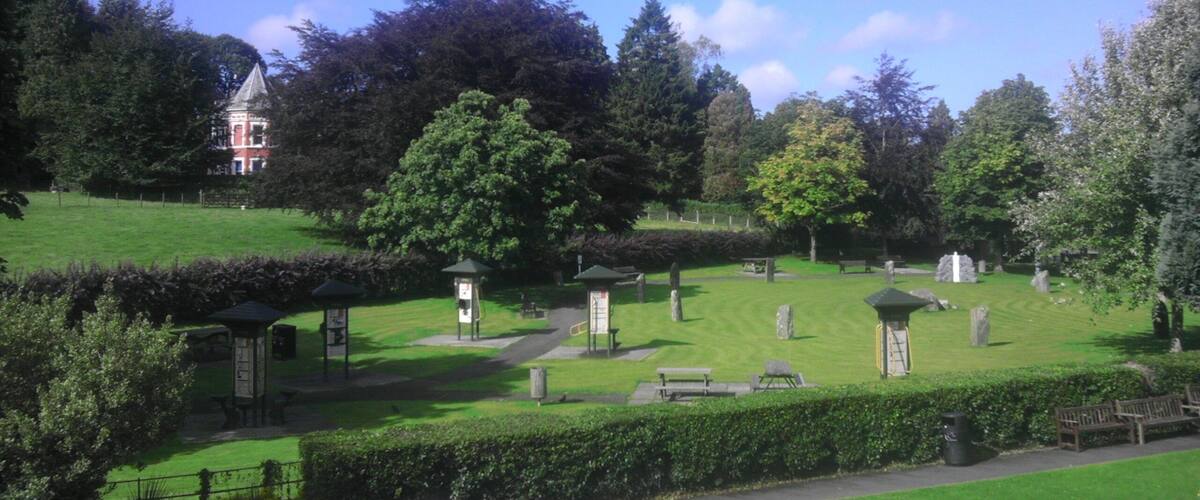 A cemetery with headstones, a gazebo, and a large tree.