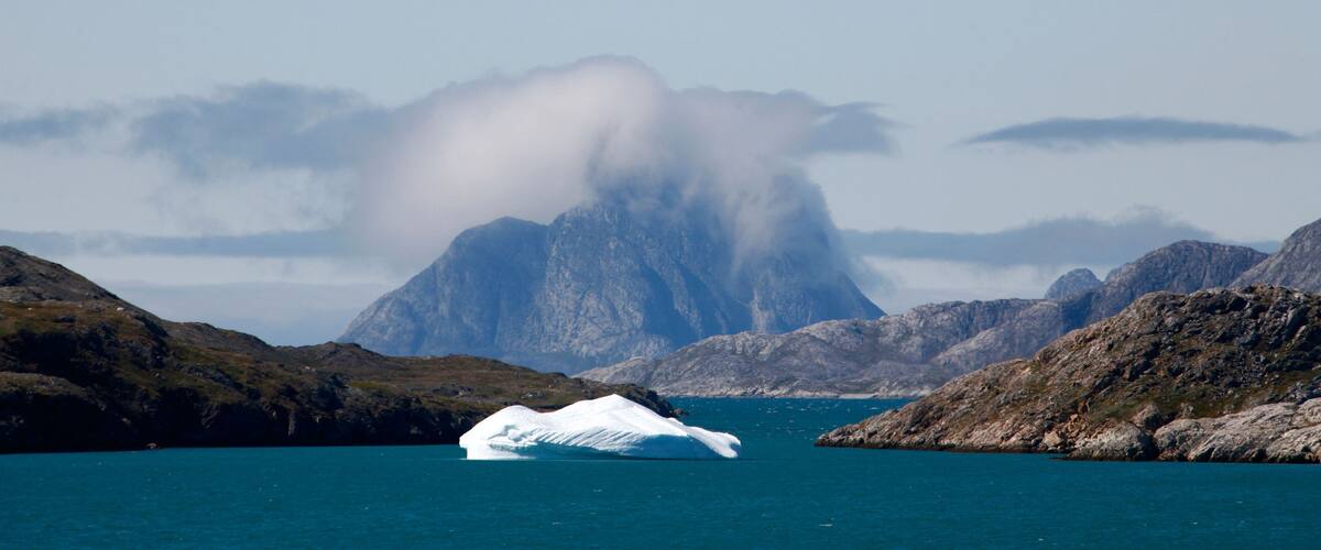 A glacier in a fjord with mountains in the background.