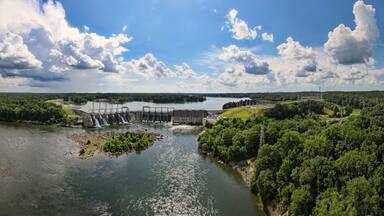 An aerial 180 degree panoramic view of a large dam and hydroelectric plant on the Catawba river in South Carolina with Lake Wylie in the background.