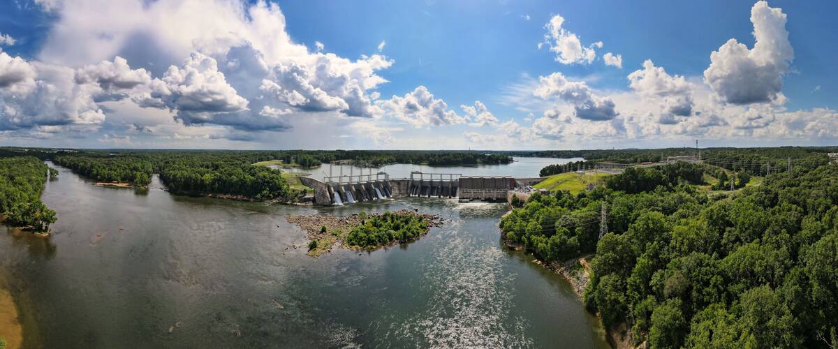A river with a dam and waterfall, surrounded by dense greenery.