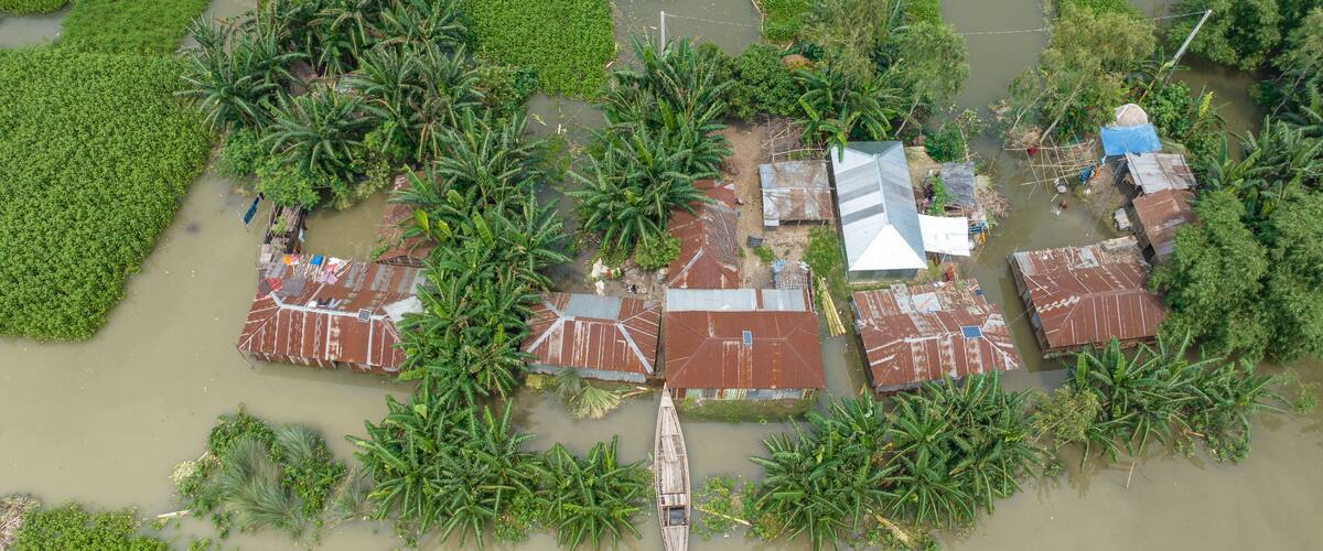 A flooded rural area with houses and a boat.