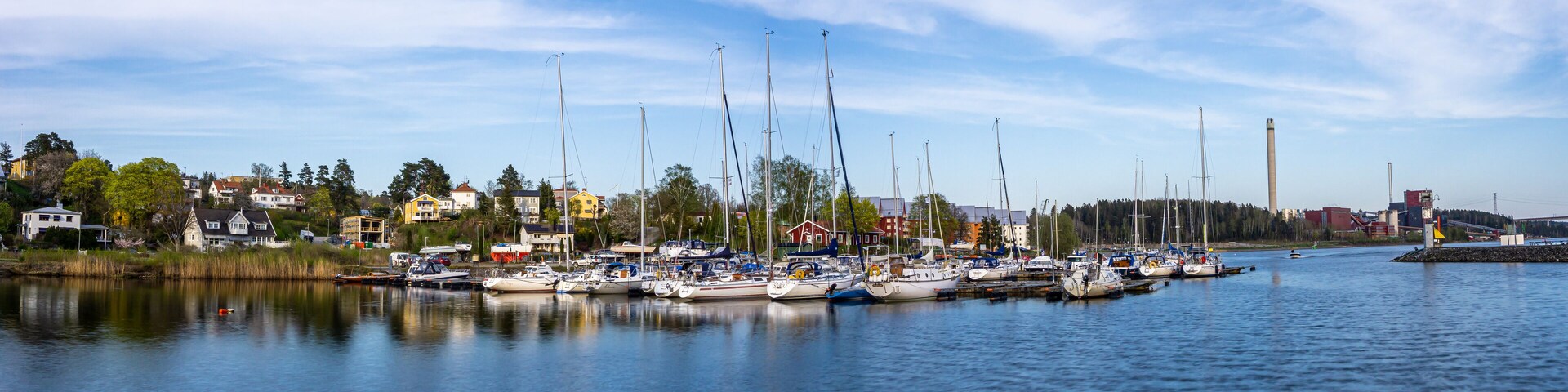 A marina with several boats docked along the shore, surrounded by houses and trees.