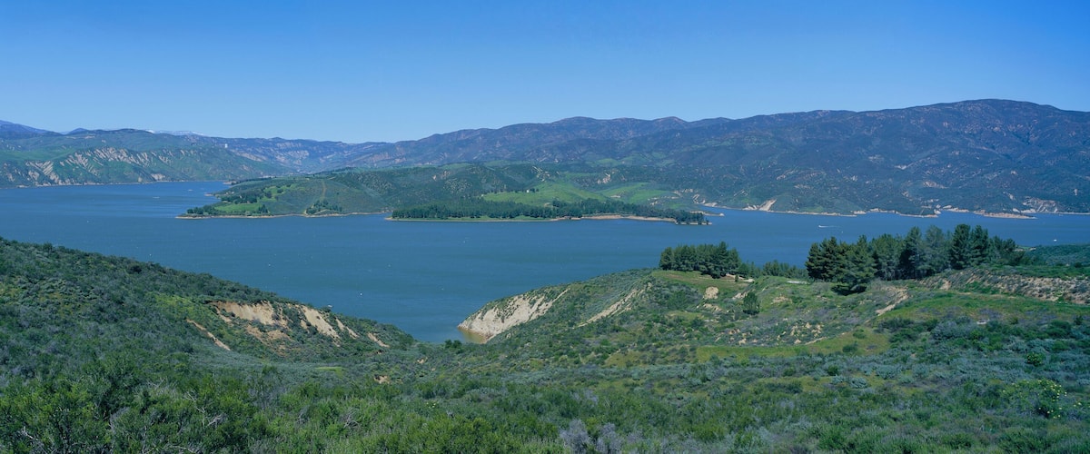 Panoramic view of Lake Castaic with green rolling hills and mountains near Interstate 5 north of Los Angeles in springtime, California