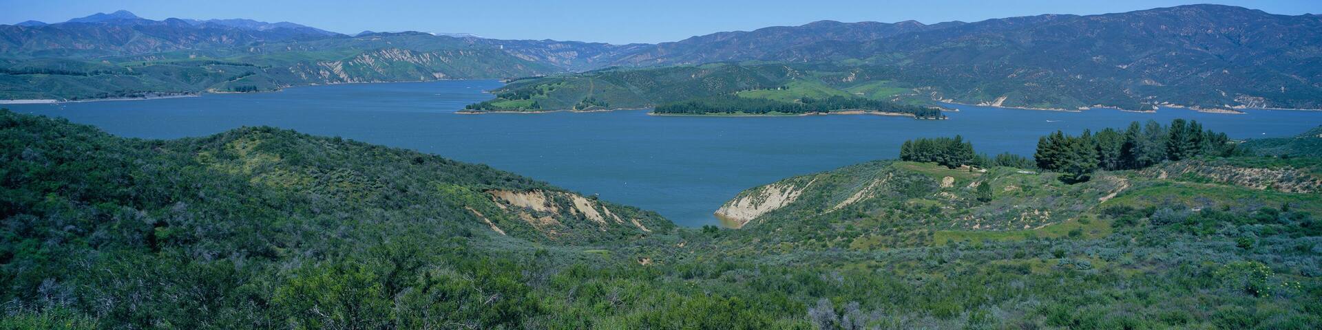 Panoramic view of Lake Castaic with green rolling hills and mountains near Interstate 5 north of Los Angeles in springtime, California