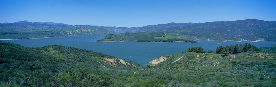 Panoramic view of Lake Castaic with green rolling hills and mountains near Interstate 5 north of Los Angeles in springtime, California