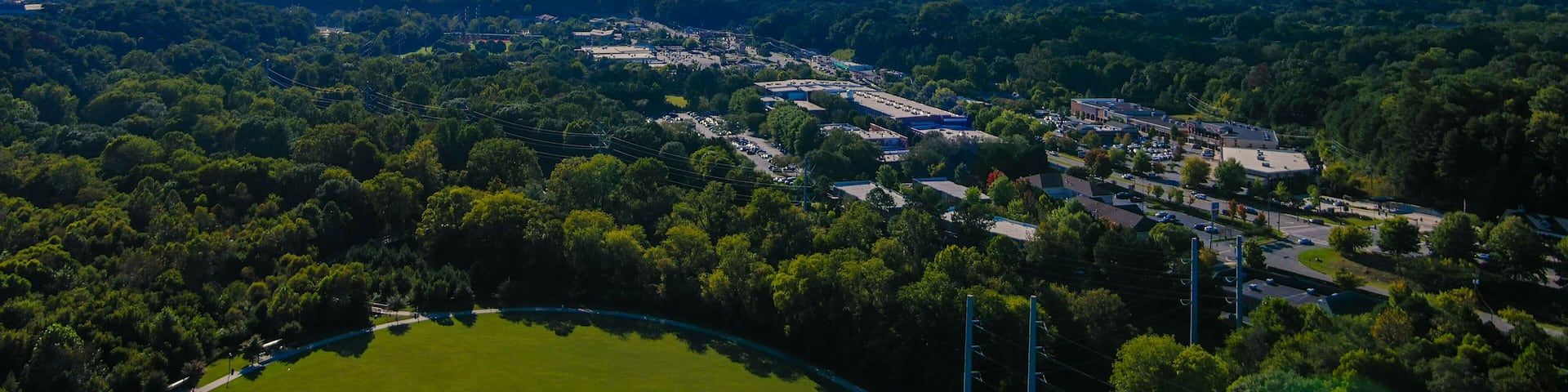 an aerial shot of the vast miles of lush green trees and grass with buildings nestled among the trees and powerful clouds at sunset at Etowah River Park in Canton Georgia USA