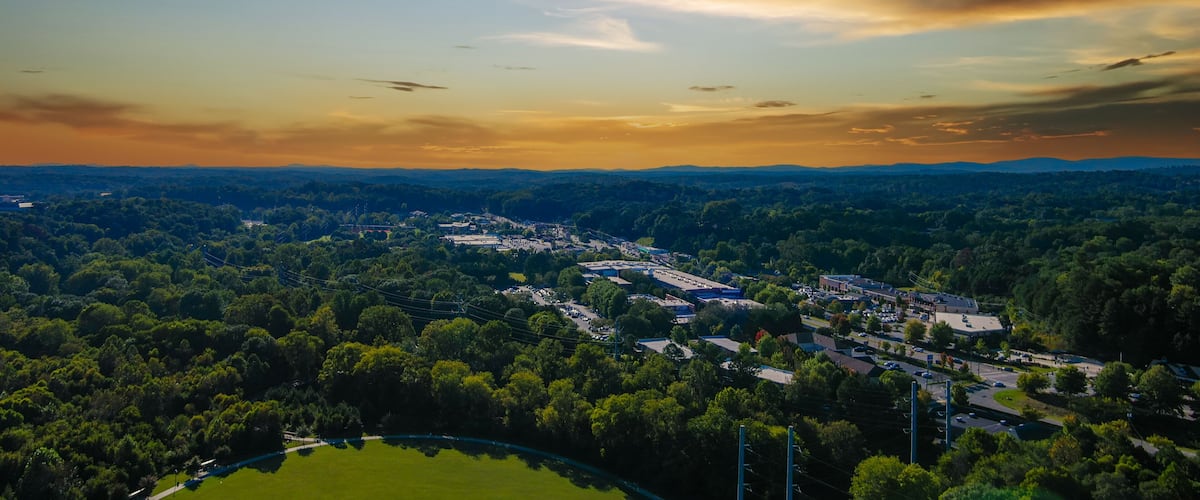an aerial shot of the vast miles of lush green trees and grass with buildings nestled among the trees and powerful clouds at sunset at Etowah River Park in Canton Georgia USA