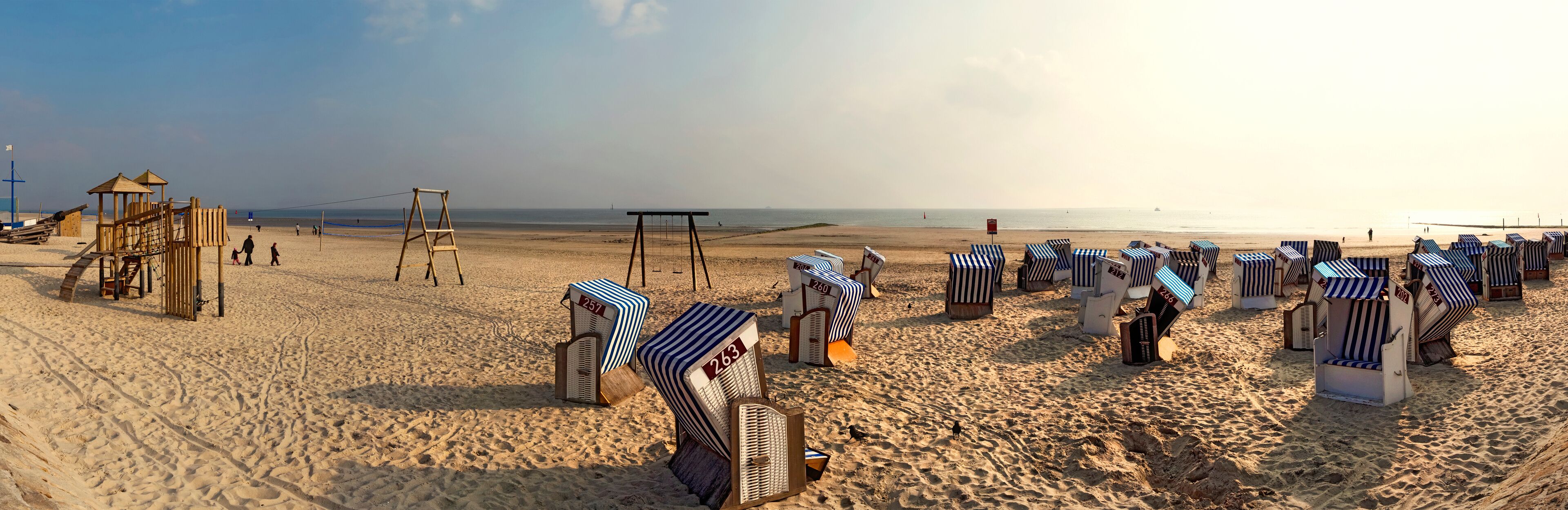 A beach with striped beach chairs and a wooden play structure.