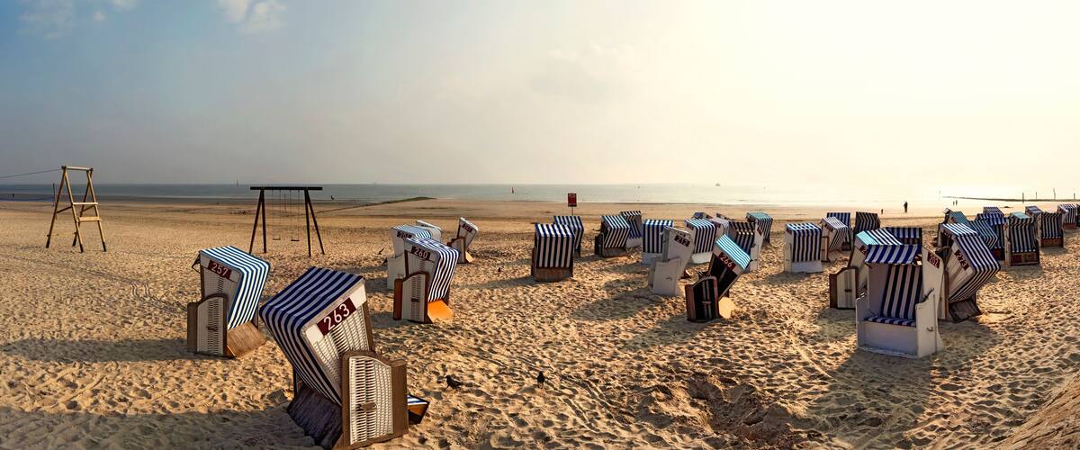 A beach with striped beach chairs and a wooden play structure.