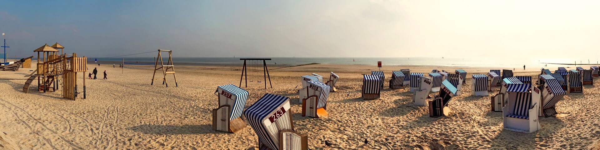 A beach with striped beach chairs and a wooden play structure.