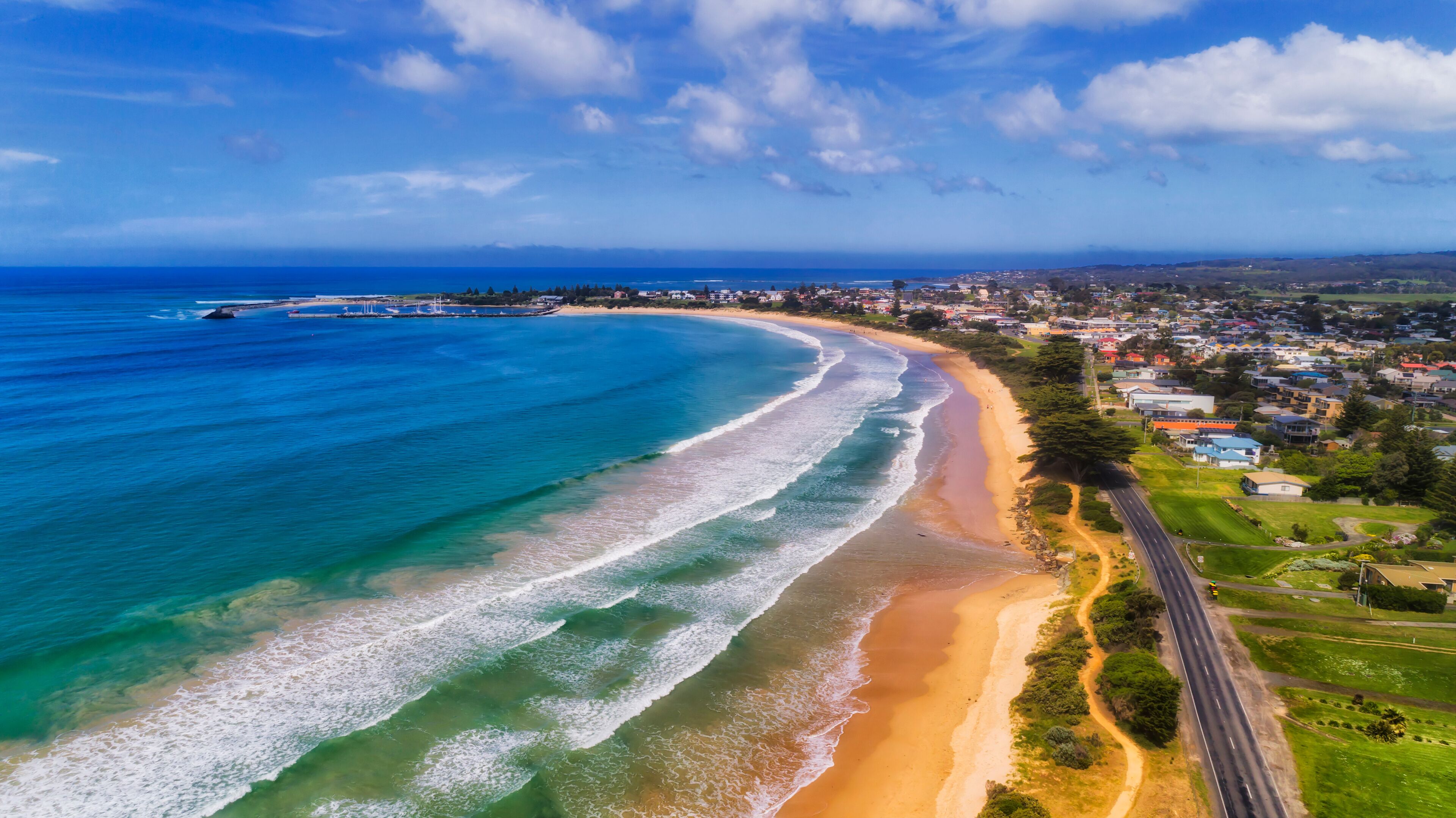 A coastal town with a beach, ocean, and a road parallel to the shore.