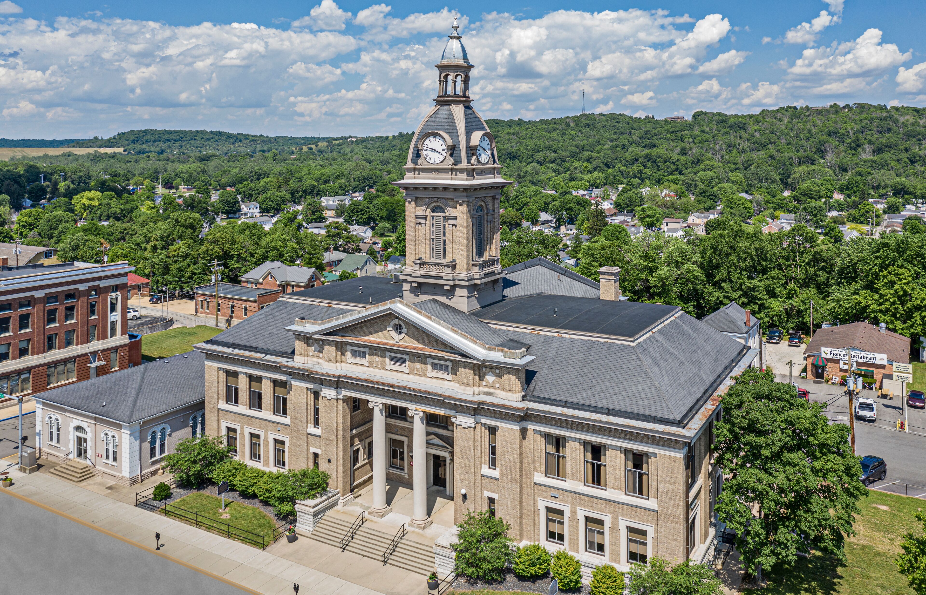 A historic building with a clock tower, surrounded by lush greenery and residential areas.