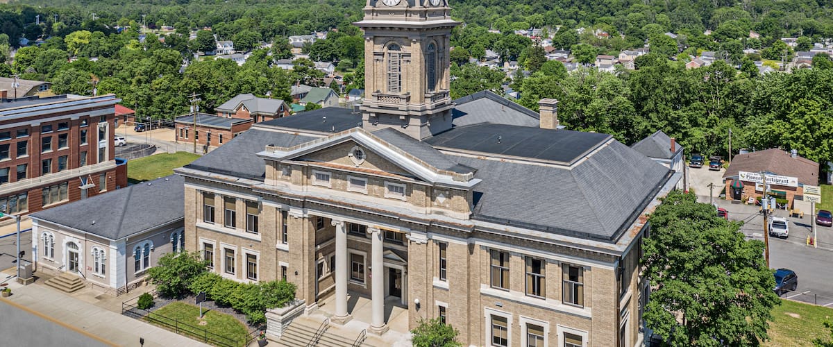 A historic building with a clock tower, surrounded by lush greenery and residential areas.