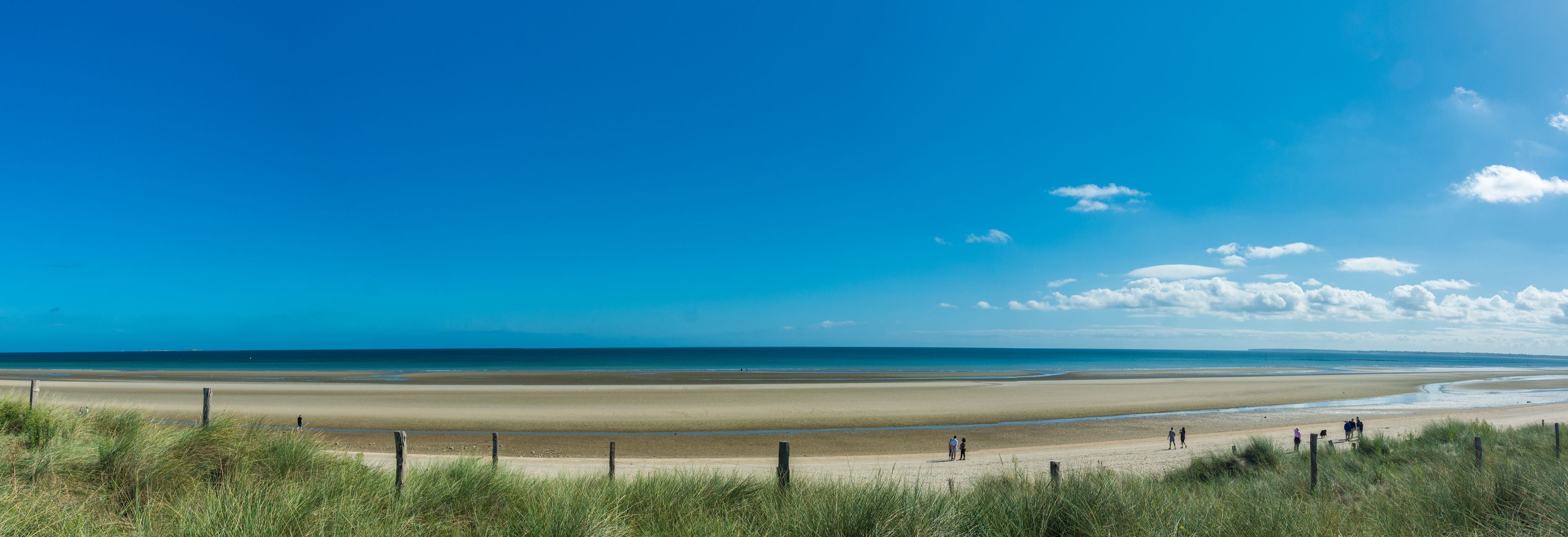 A wide beach with a clear sky and distant mountains.