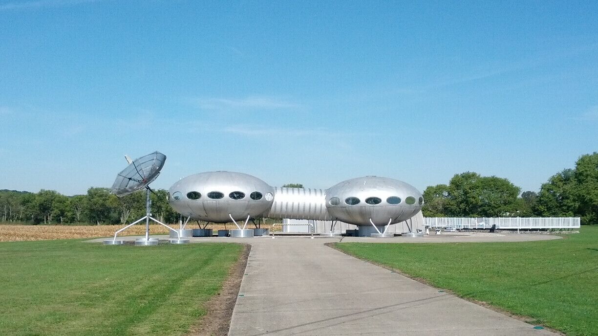A unique metallic structure resembling a futuristic vehicle with a satellite dish on the left.
