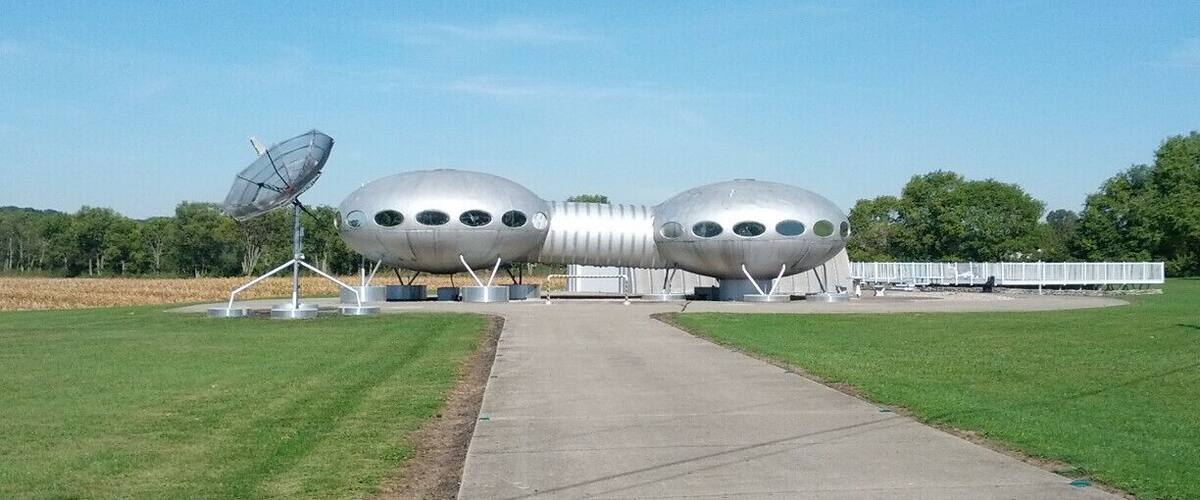 A unique metallic structure resembling a futuristic vehicle with a satellite dish on the left.