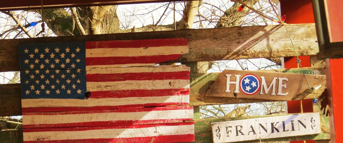 A wooden fence with an American flag and a 'HOME' sign, and a street sign reading 'FRANKLIN'.