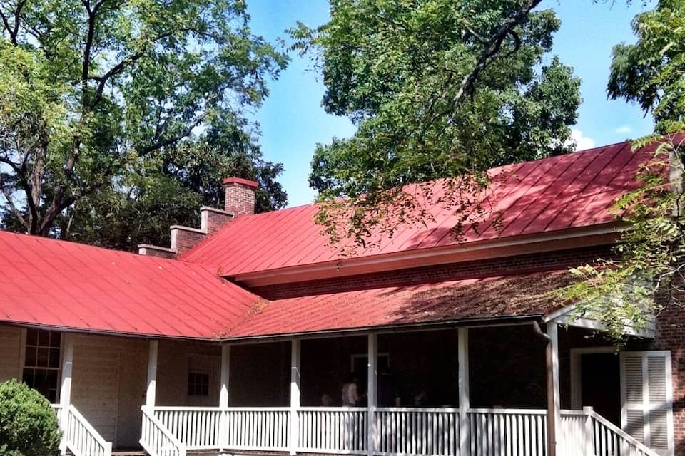 A house with a red roof, white porch, and a brick chimney.