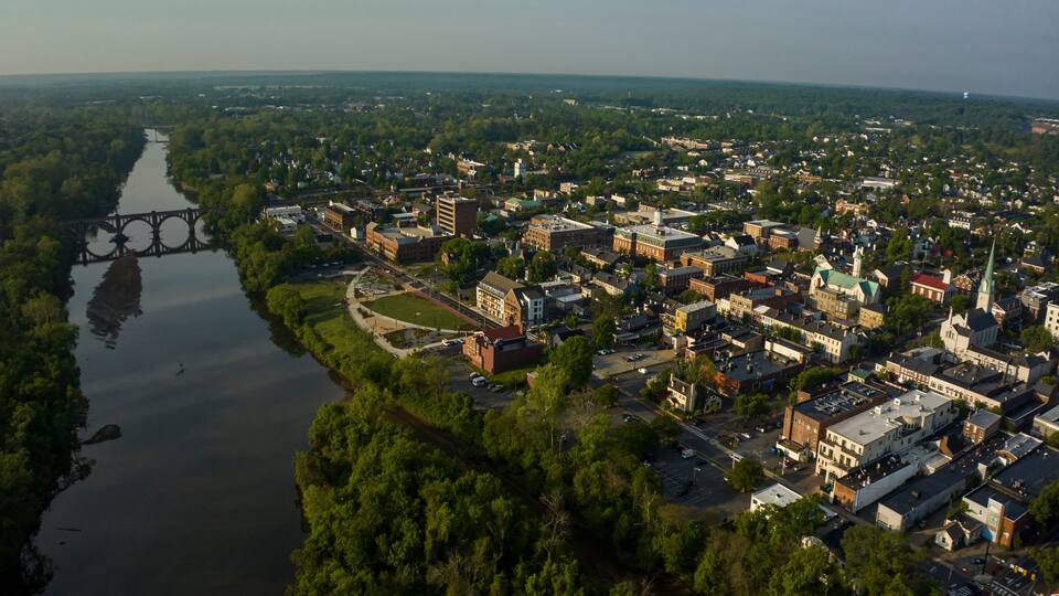 An aerial view of a town with a river, a bridge, and various buildings.