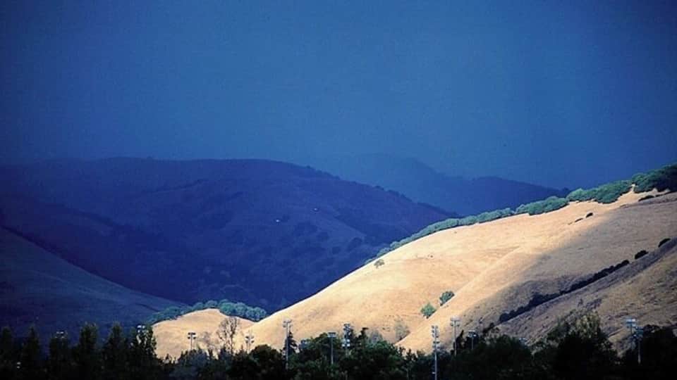 Impending Storm
This picture is from the archives...I think I took this picture in 2002/2003...
En route to running a quick errand in Fremont, CA, where we lived, I was driving by Lake Elizabeth. On the east side of the lake are the Mission Hills. Since I was driving on the west side of said lake, I had an excellent view of the hills, and was witness to an extraordinary sight. Storm clouds coming up from the south had some ridges in complete shadow, while an adjoining ridge, which was not under the influence of the storm yet, was spot lit by sun. I could see the storm traveling north rapidly, and I knew that the situation would not last. Parking the car, I raided my camera bag for my camera and a telephoto, and with tripod in hand, ran to the water's edge. I managed to setup and expose a few frames, before the sunlit ridge came under the shadow of the storm. The magic was gone and the entire landscape turned a uniform dull gray.
I don't remember any technical details other than that the camera used was a Nikon F100. I owned the Nikkor 80-200 mm f2.8 lens then, which I was partial to, so that may well have been my lens of choice for this shot. Similarly, I used to shoot with Fuji transparencies at the time, so my guess is that I used Fuji Velvia for this shot.