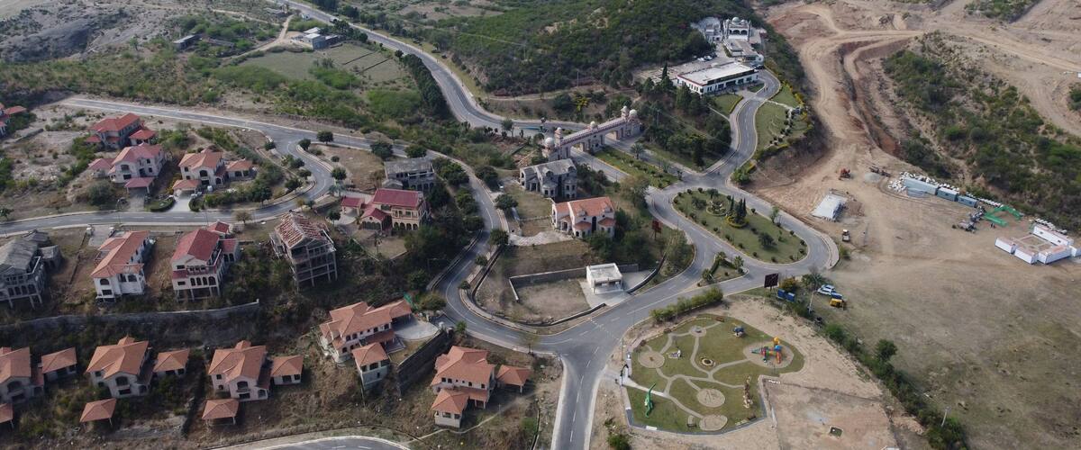 An aerial view of a residential area with winding roads, houses, and a large building with domed structures.