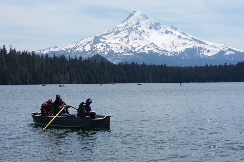 Un grupo de personas en un bote en un lago, con una montaña nevada al fondo.