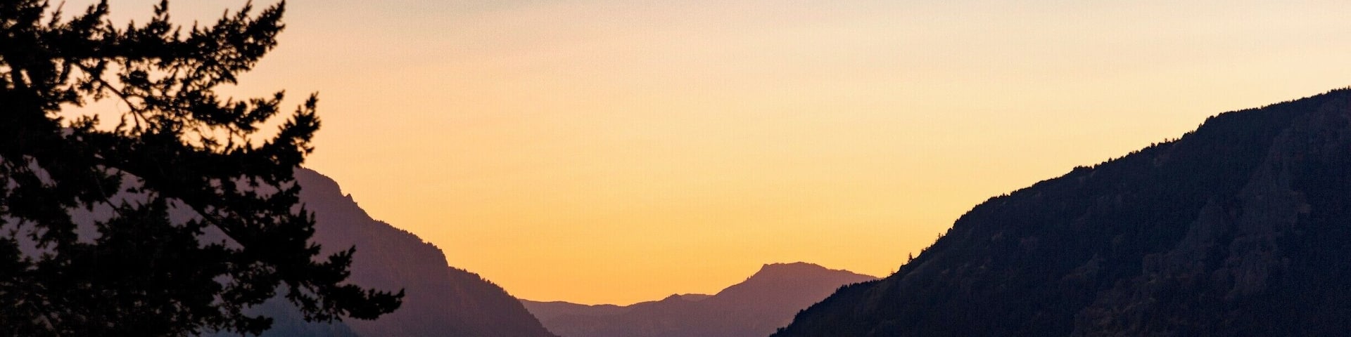 A calm lake surrounded by mountains at sunset.