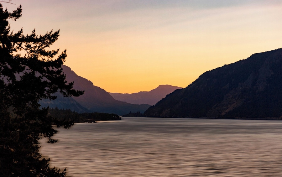 A calm lake surrounded by mountains at sunset.