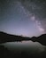 Un ciel étoilé au-dessus d’une chaîne de montagnes se reflète dans un lac paisible.