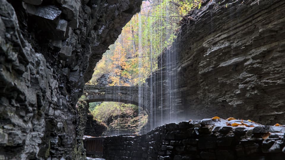 rainbow ralls at watkins glen state park (waterfall in a gorge with stone bridge, staircase, glacial layered rock formation) falling water, stream, autumn colors, leaves changing, fall foliage