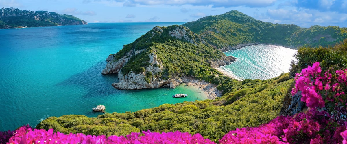 A coastal landscape with a small island, turquoise waters, and lush greenery.
