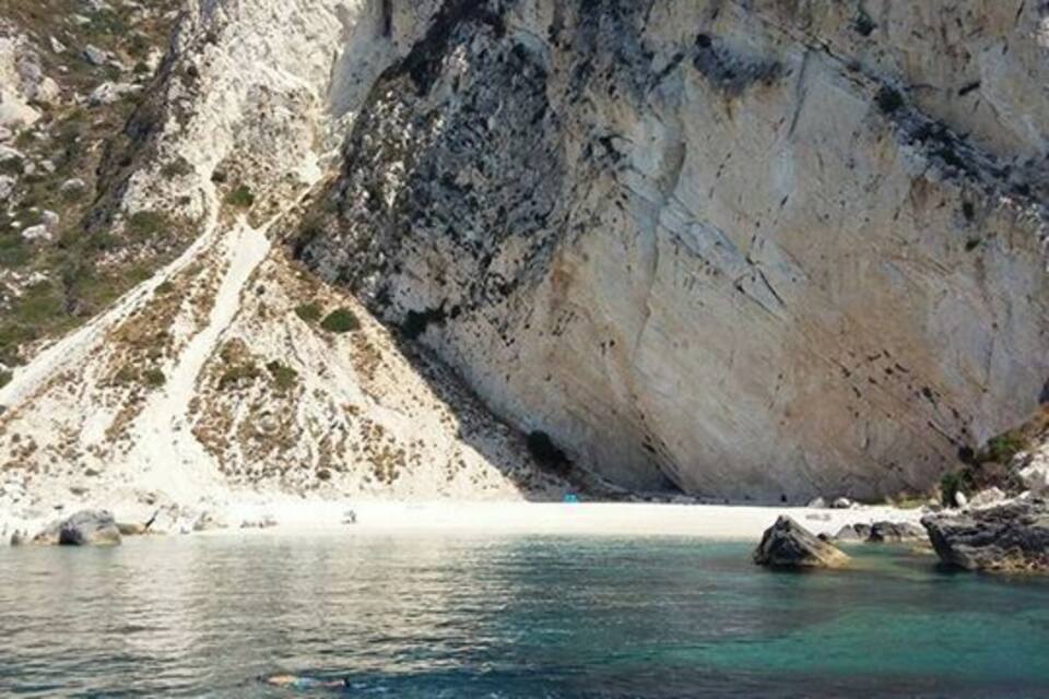Eine felsige Küste mit klarem, blauem Wasser und einem weißen Sandstrand.