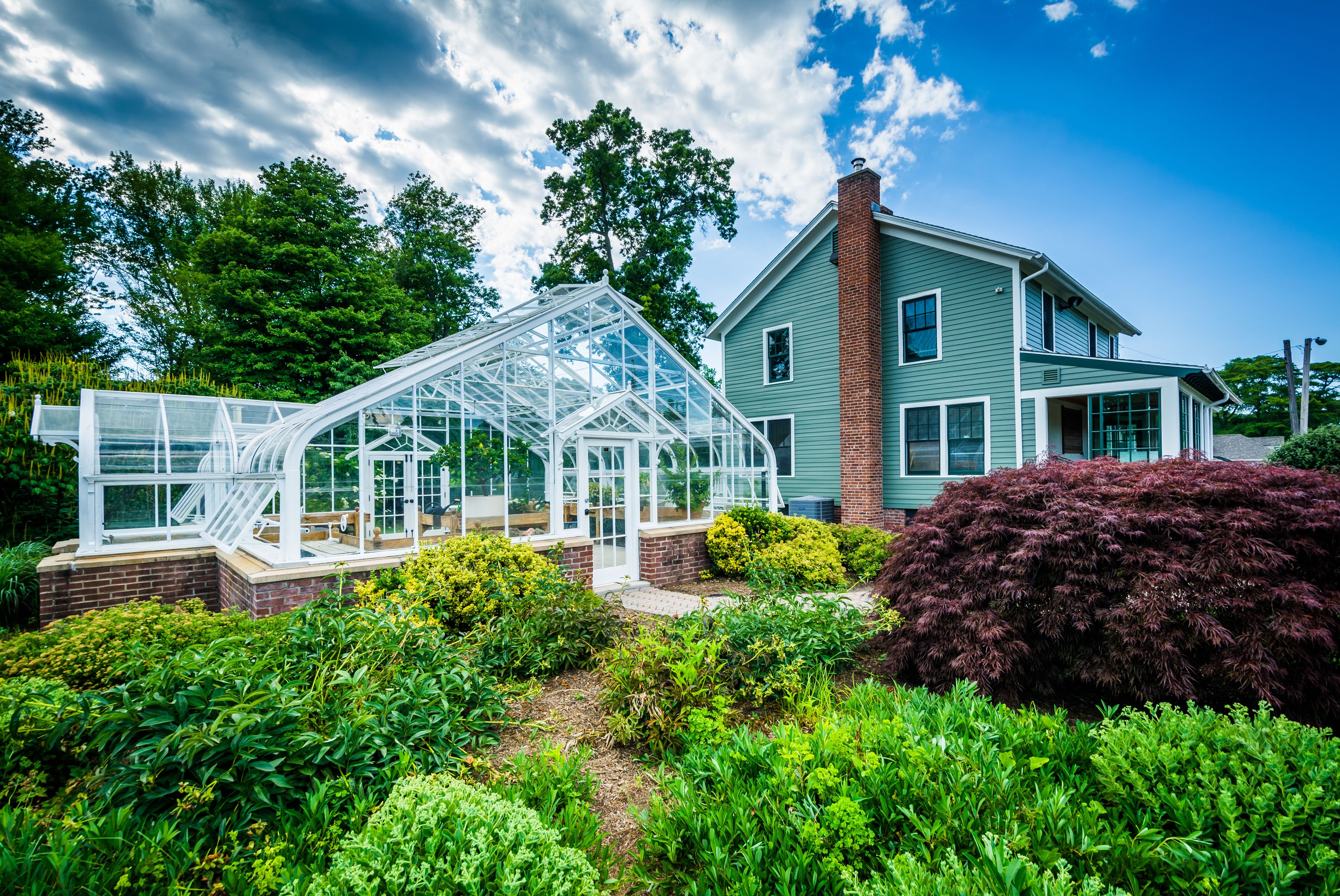 A large green house with a glass greenhouse attached.