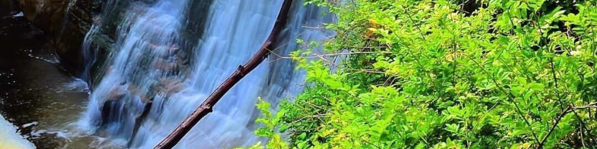 A multi-tiered waterfall surrounded by lush greenery.