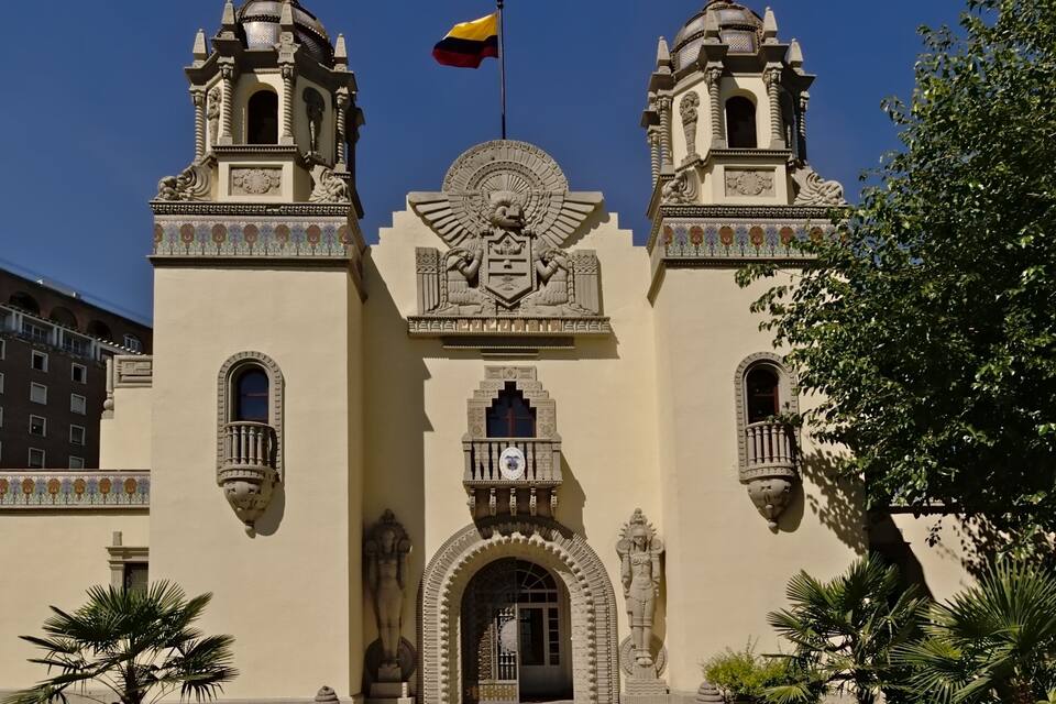 A historic building with two towers, a central archway, and a flag.