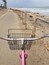 Una playa con una cerca de metal y una bicicleta rosa al frente.