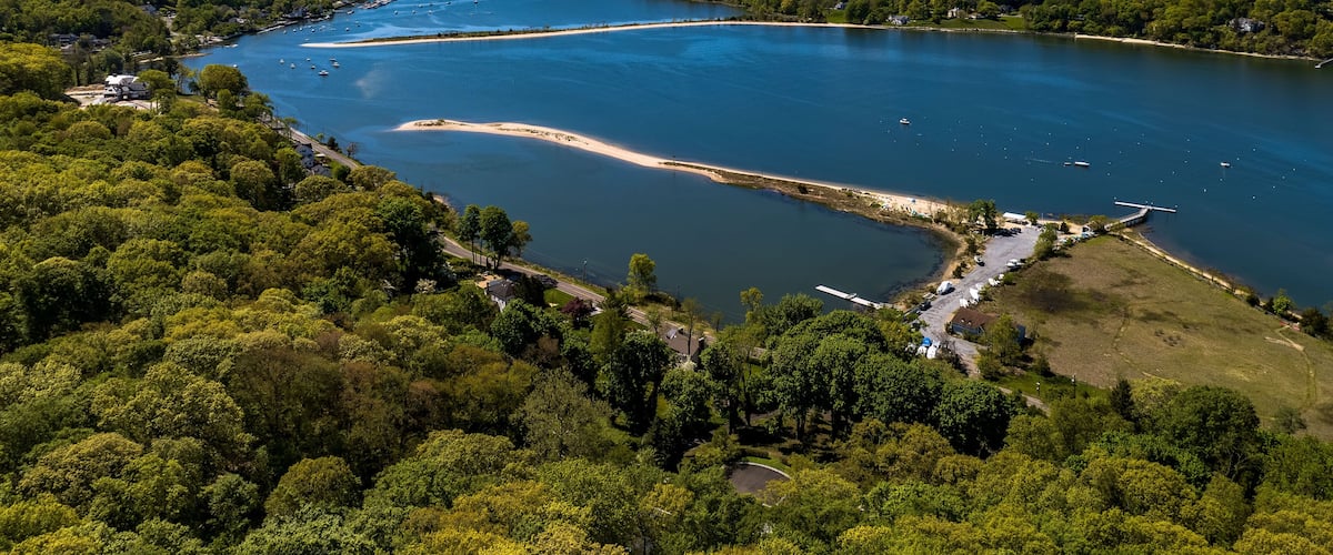 Aerial view over a large sandbar in the green waters of Oyster Bay in Lloyd Harbor on Long Island