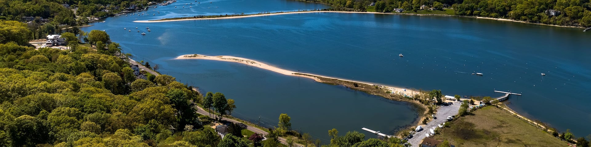 A large lake surrounded by dense forest, with several boats anchored near the shore.